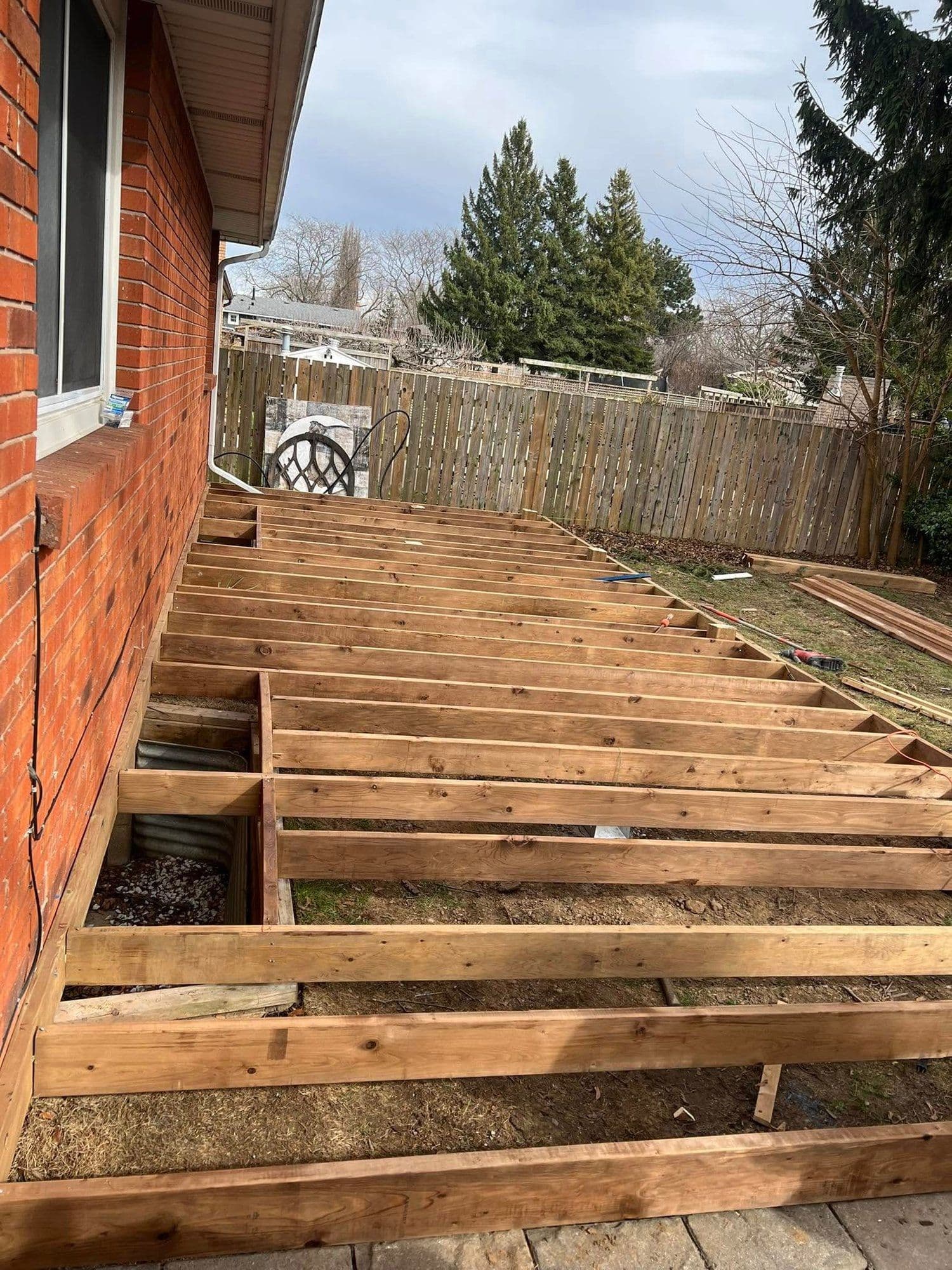 Pressure-treated deck framing built off the back of a brick house