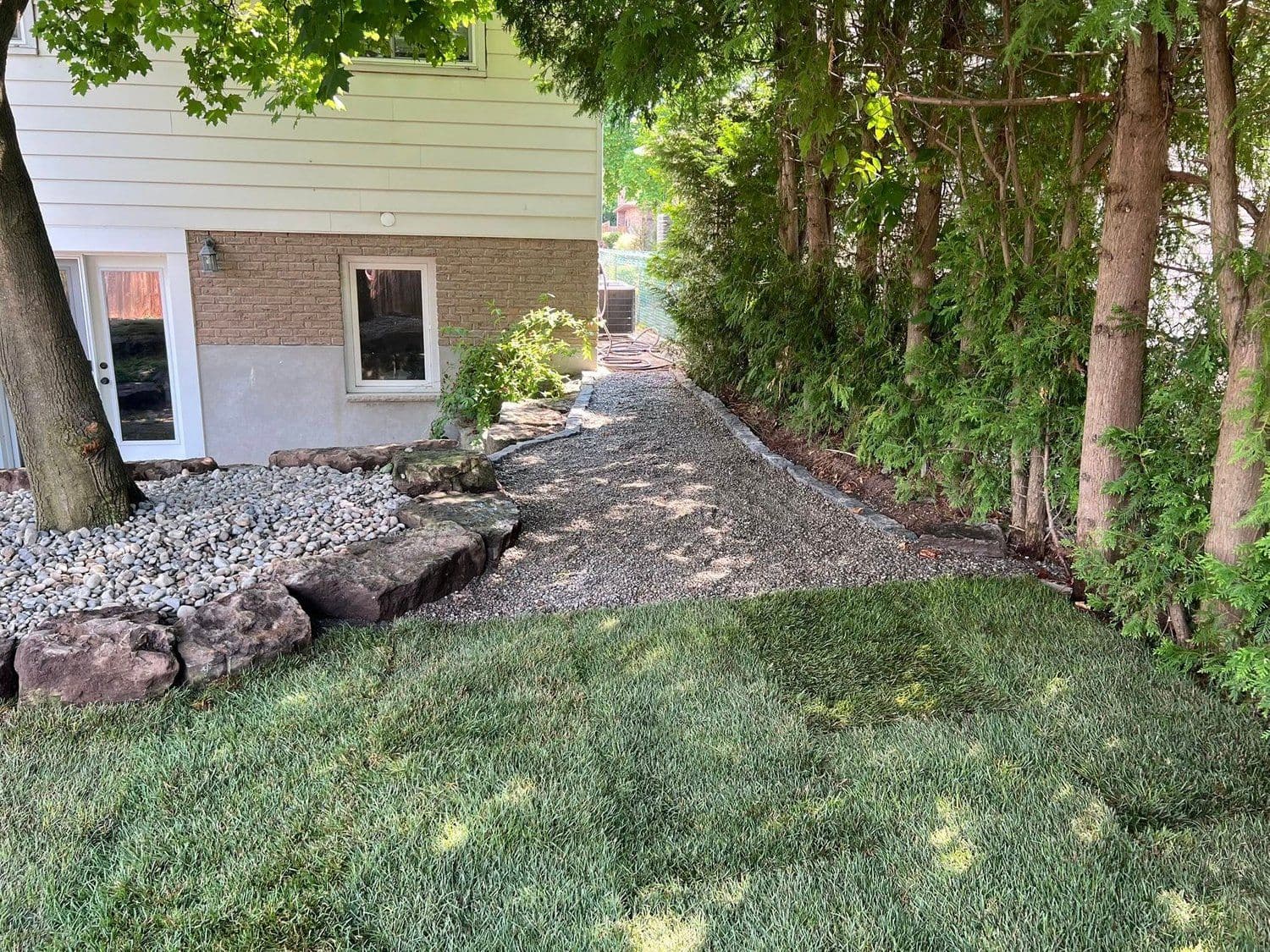 Side yard with armor stone border and gravel walking path
