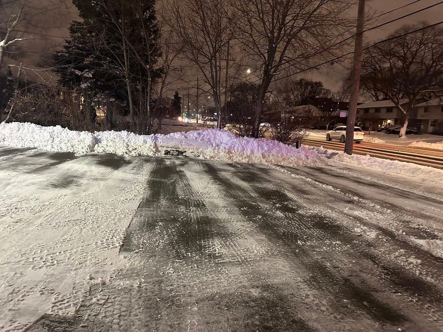 Plowed residential driveway and street at night during a Niagara snowfall
