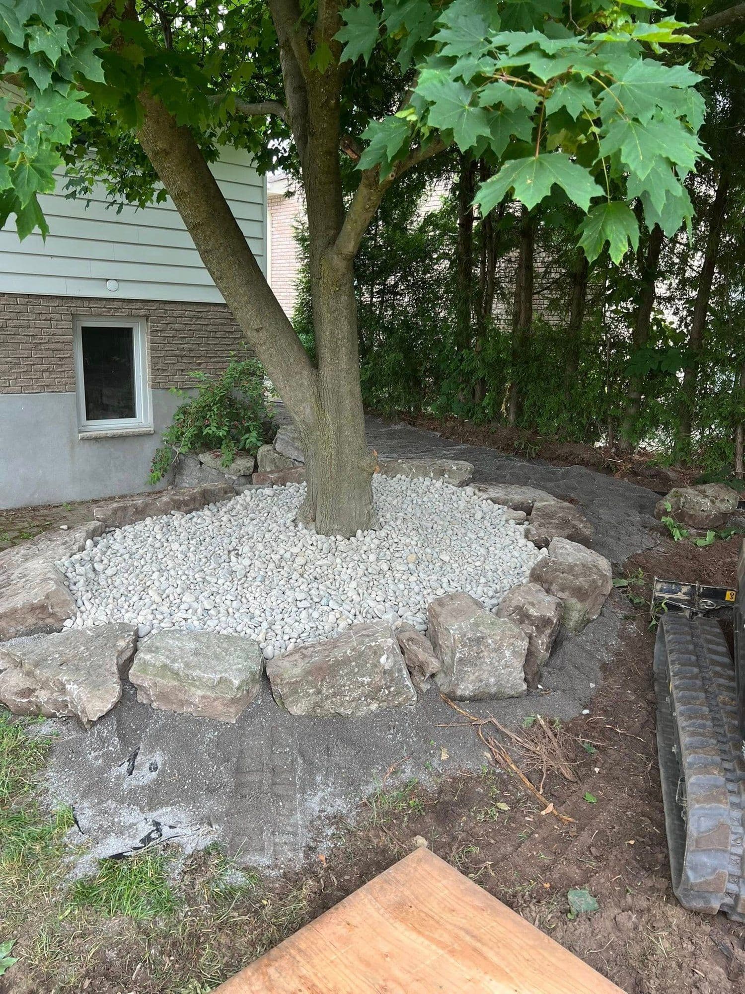 Backyard tree ring built with armor stone and white river rock